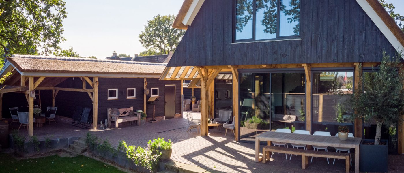 Houten woning en kleinere houten schuur met rieten dakbedekking